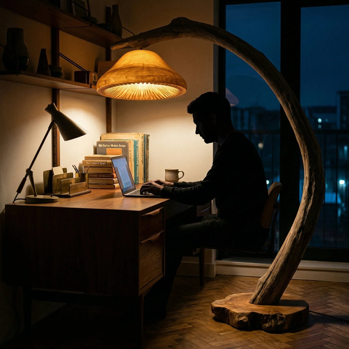 Man werkend aan houten bureau verlicht door een drijfhout booglamp